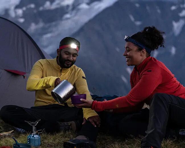 Two campers are enjoying the joy of camping at night wearing headlamp