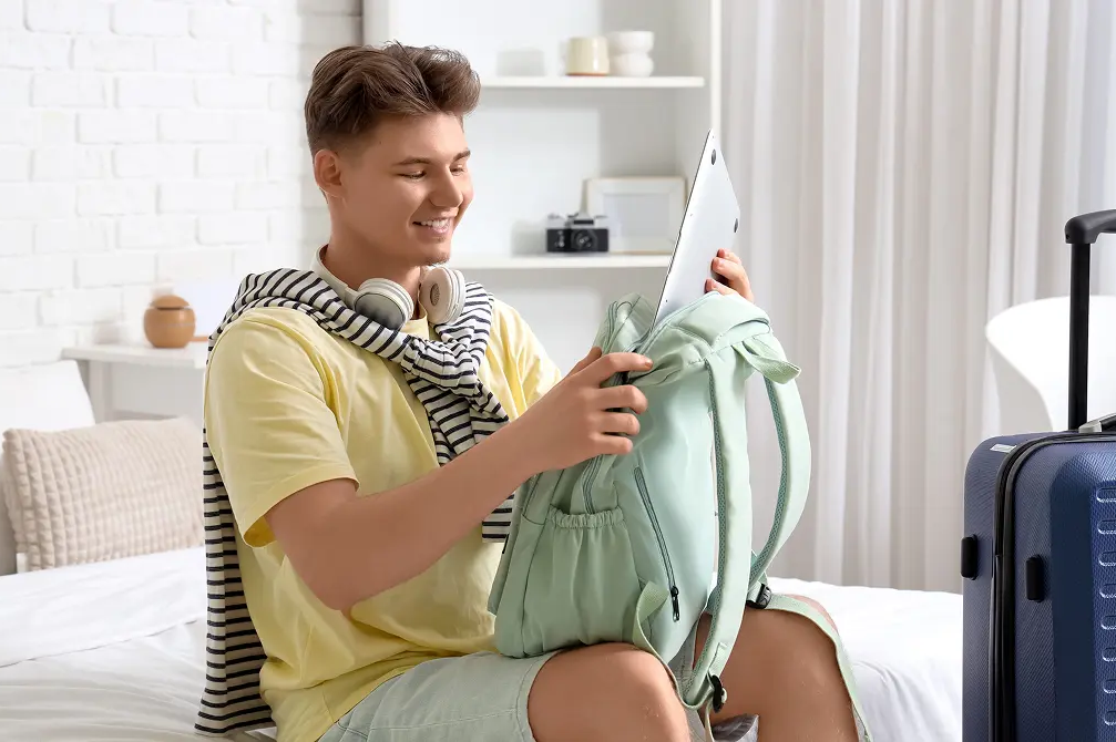 Chłopak chowający laptopa do plecaka