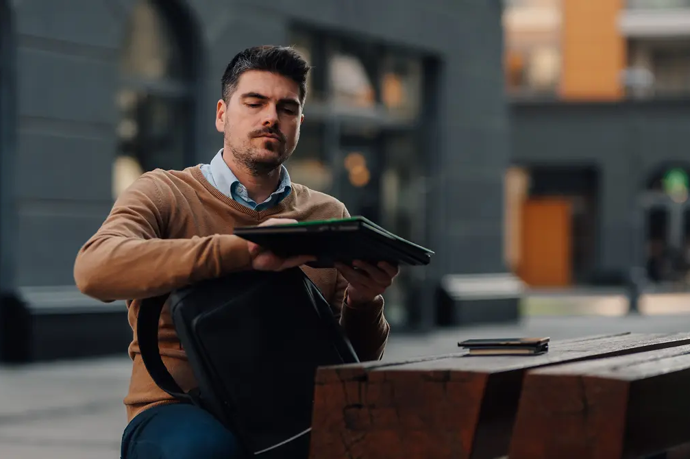 Mężczyzna wkładający laptopa do plecaka