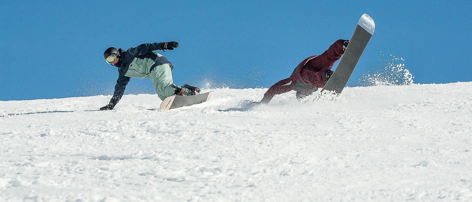 mężczyźni w odzieży snowboardowej zjeżdżający na deskach snowboardowych 
