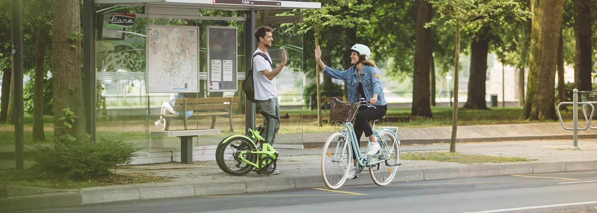 A woman hi-fives a man whilst cycling by.