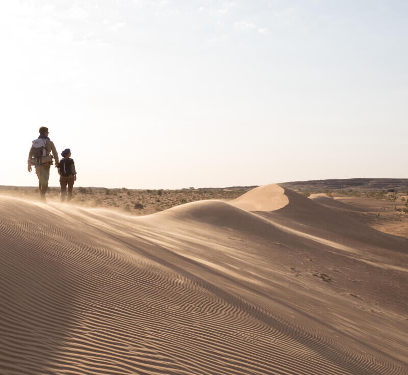Trekkeurs marchant sur une dune de sable dans le desert