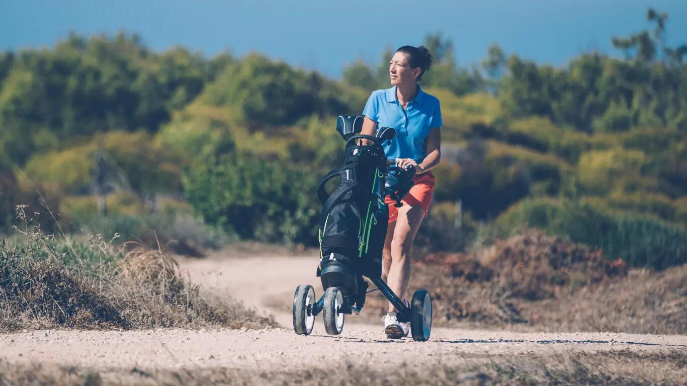 Kobieta idaca z wózkiem na kije golfowe