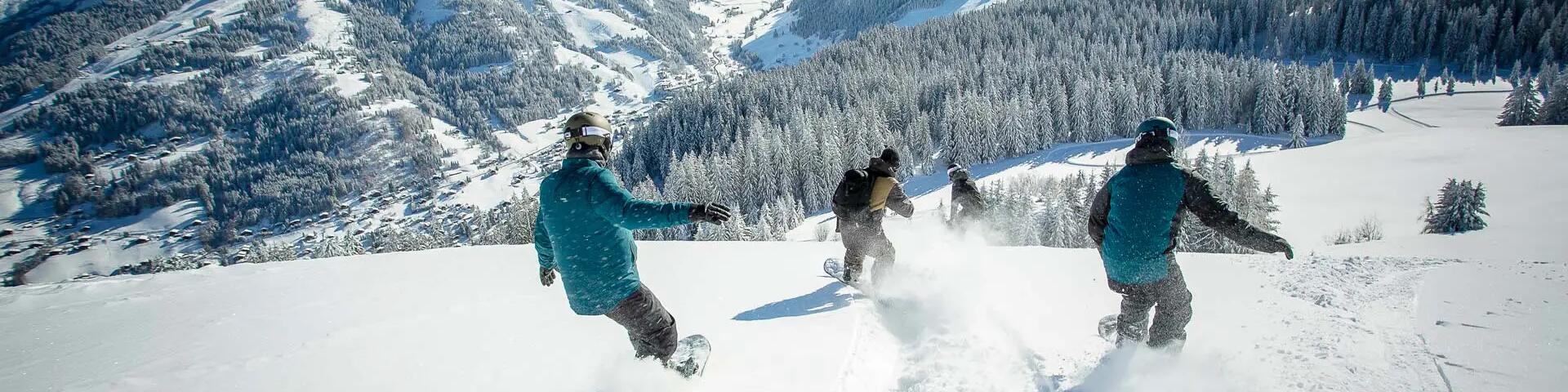 ludzie zjeżdżający na snowboardzie ze stoku