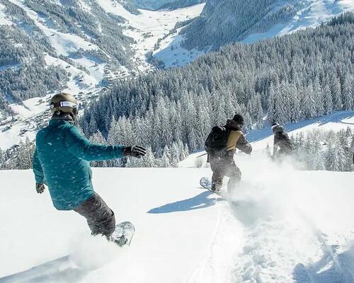 ludzie zjeżdżający na snowboardzie ze stoku