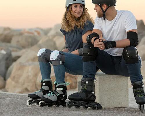 Two people sitting outside and wearing inline skates