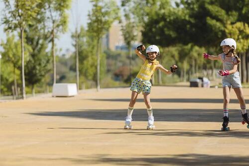 Two children roller skating outdoors