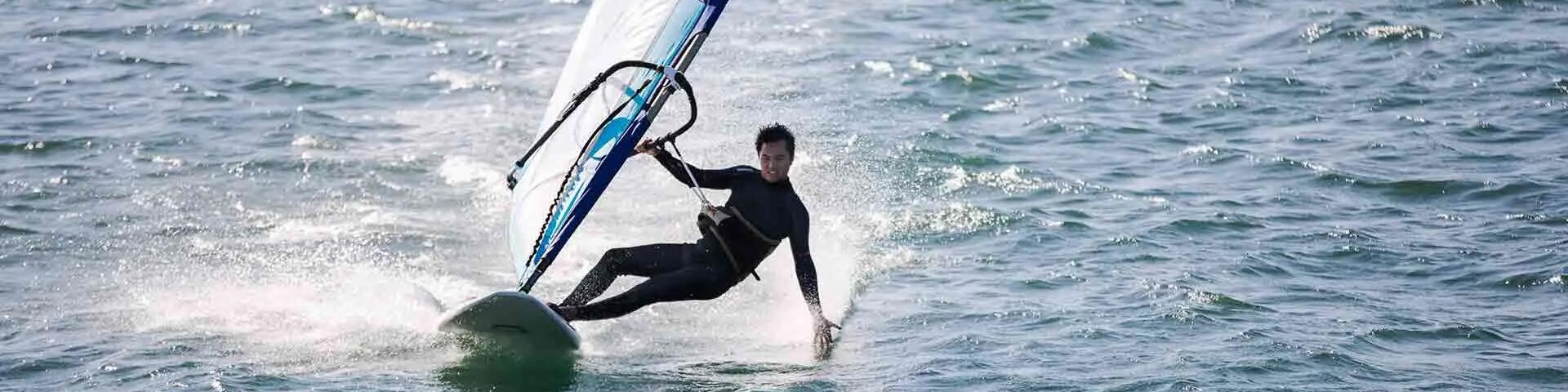 mężczyzna w piance pływackiej uprawiający windsurfing