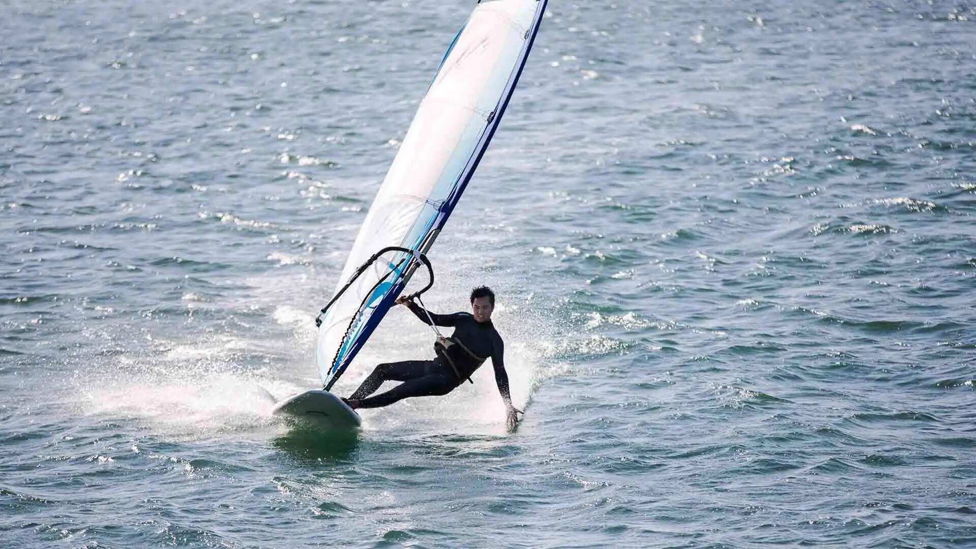 mężczyzna w piance pływackiej uprawiający windsurfing