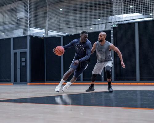 Man dribbling basketball around opponent