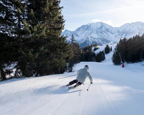 mężczyzna zjeżdżający ze stoku na nartach w odzieży narciarskiej