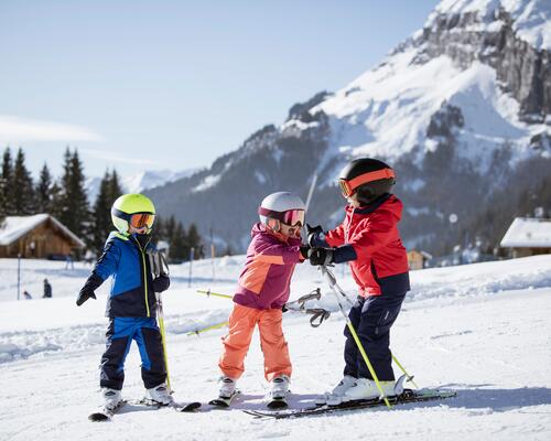 dzieci w strojach narciarskich na stoku