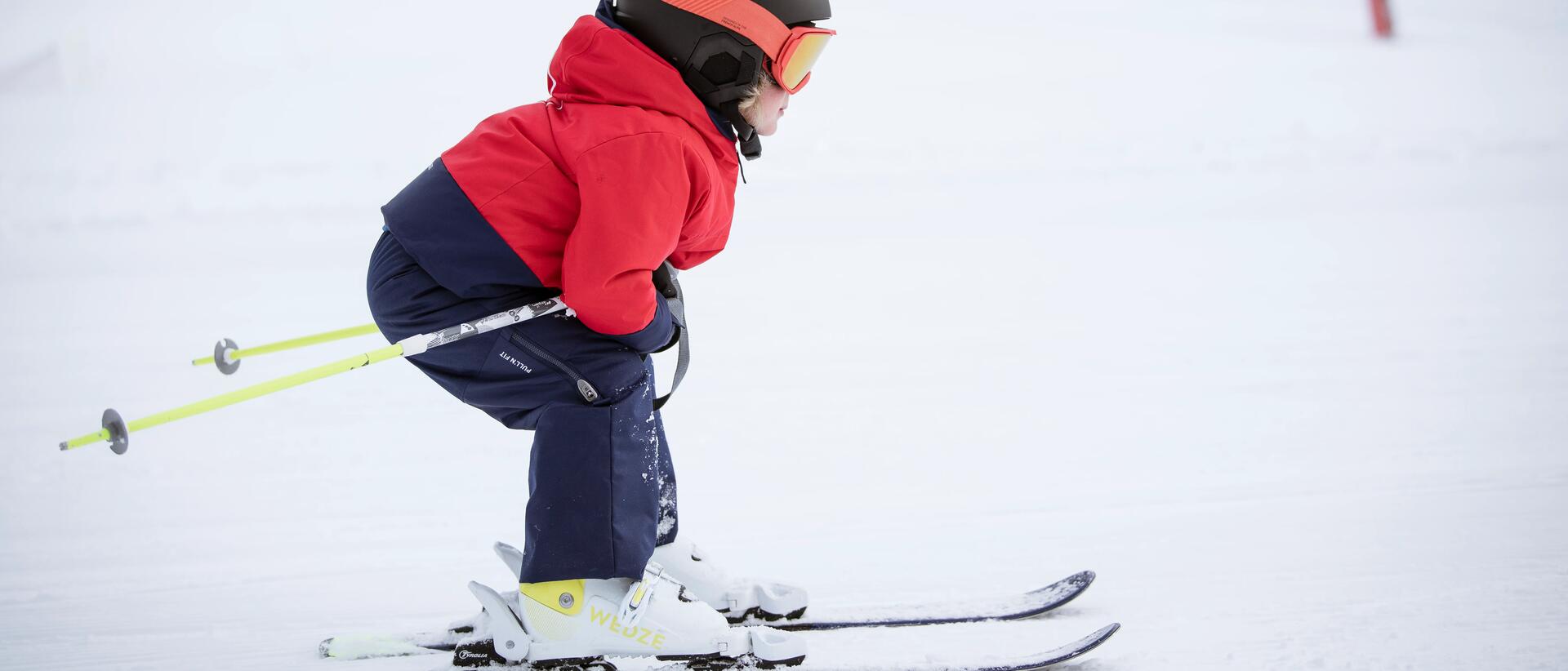 dziecko z kijkami  narciarskimi jadące na nartach