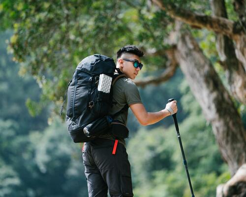 mężczyzna z plecakiem na plecach i kijem trekkingowym w ręce
