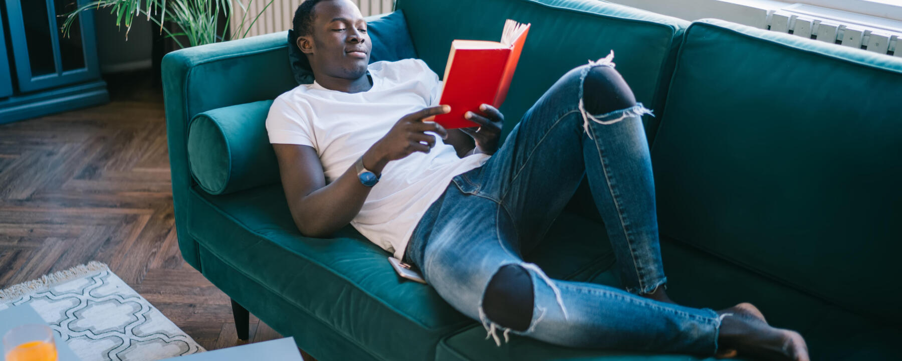 un homme lisant un livre sur son canapé