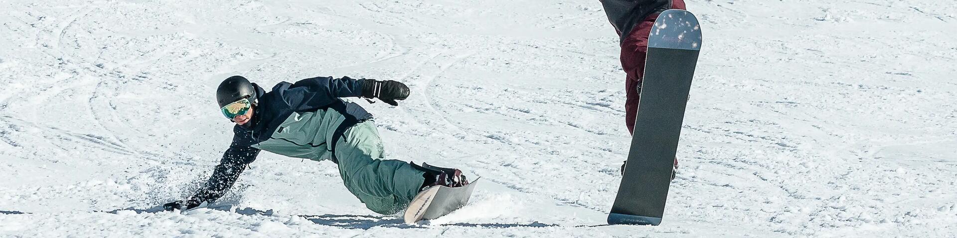 mężczyźni w kaskach i goglach jadący na deskach snowboardowych 