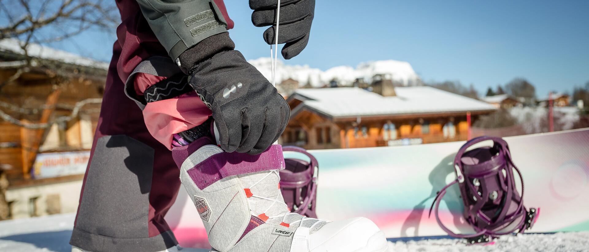 kobieta odpinająca buty snowboardowe