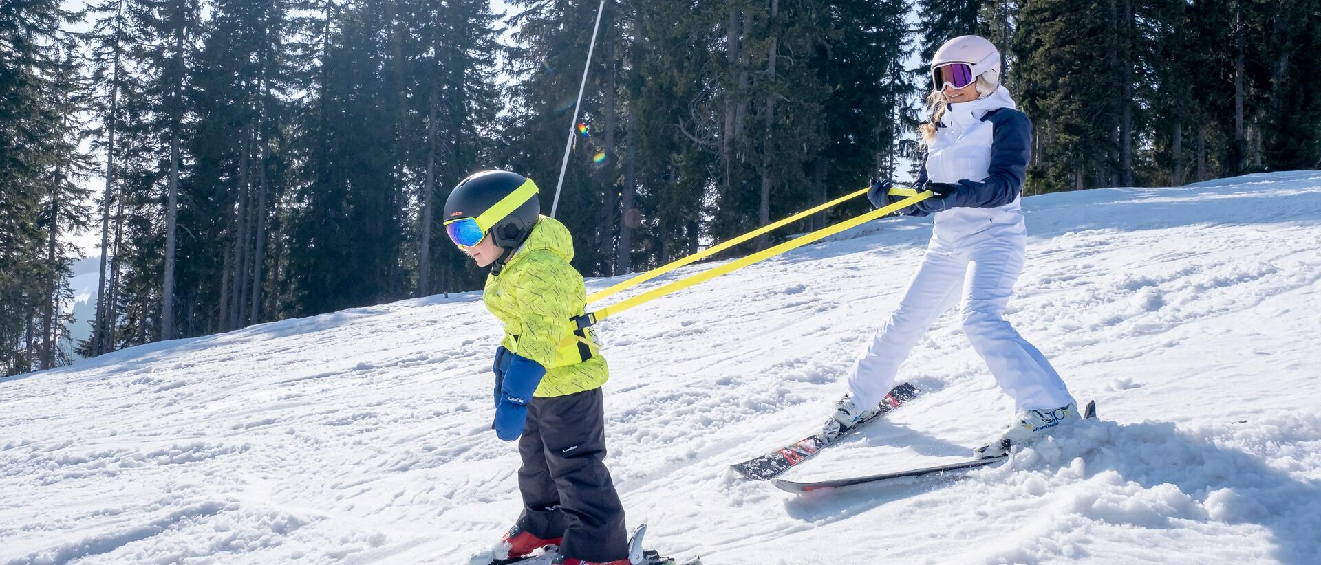 kobieta z dzieckiem zjeżdżają ze stoku na nartach