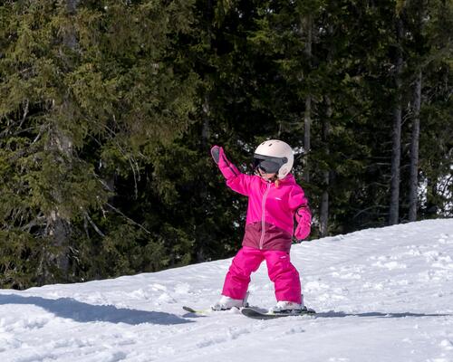 dziewczynka w różowym stroju narciarskim  zjeżdżająca ze stoku 