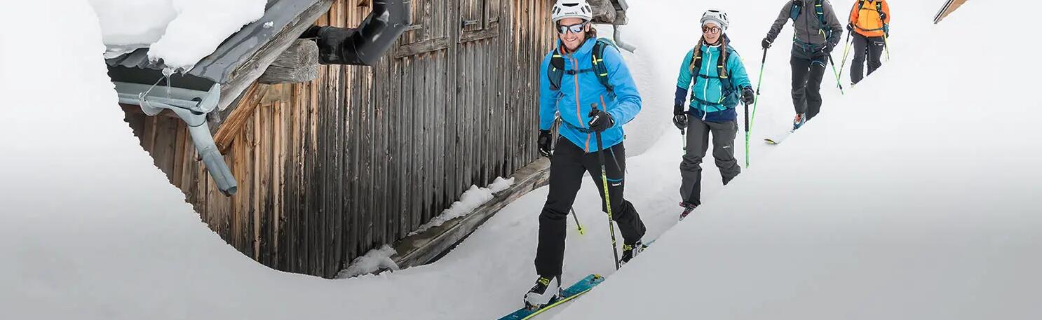 3 osoby na nartach w strojach narciarskich