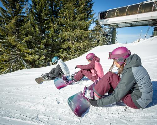 ludzie w strojach snowboardowych siedzący na śniegu