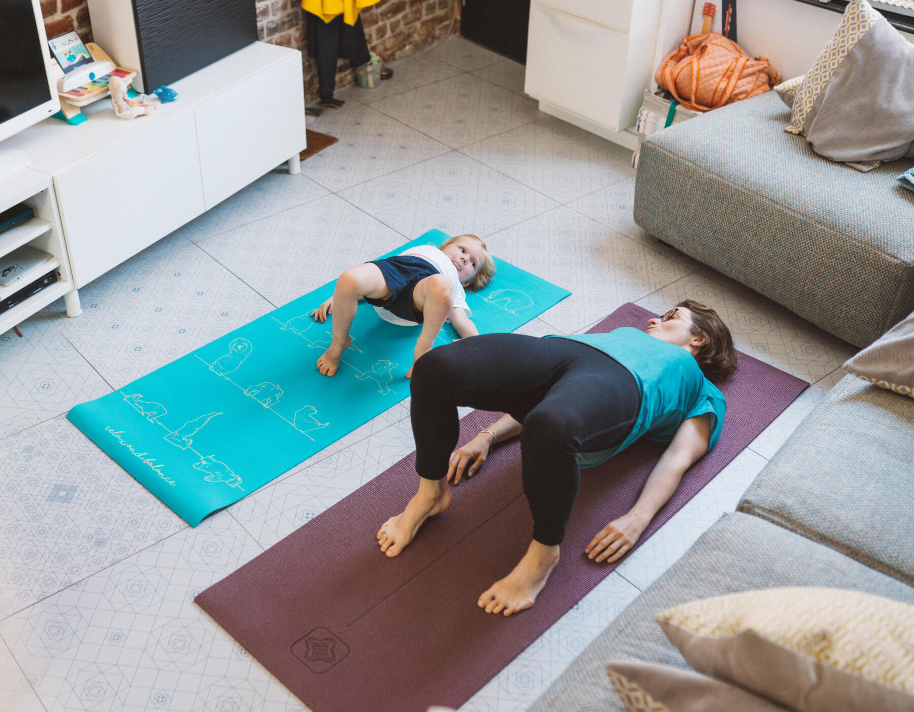 En mamma och hennes dotter som gör yogaövningar på mattor