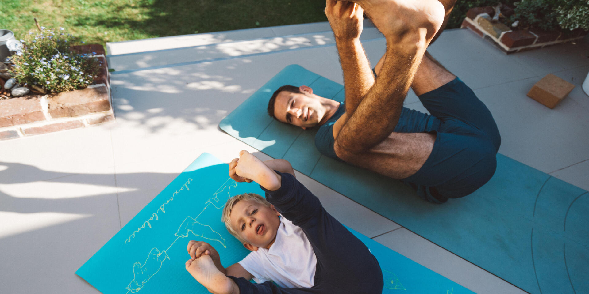 un père et son fils faisant des exercices au sol sur leur terrasse