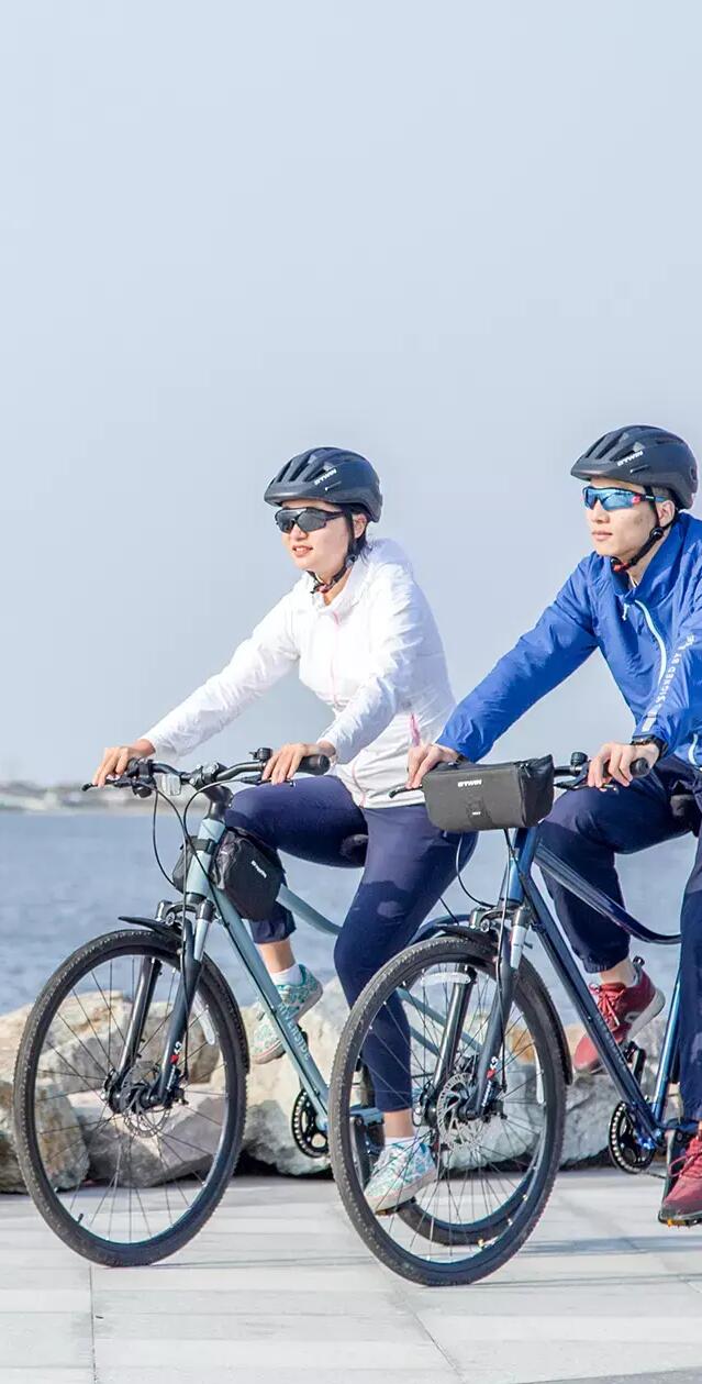Man and woman riding their bike near sea