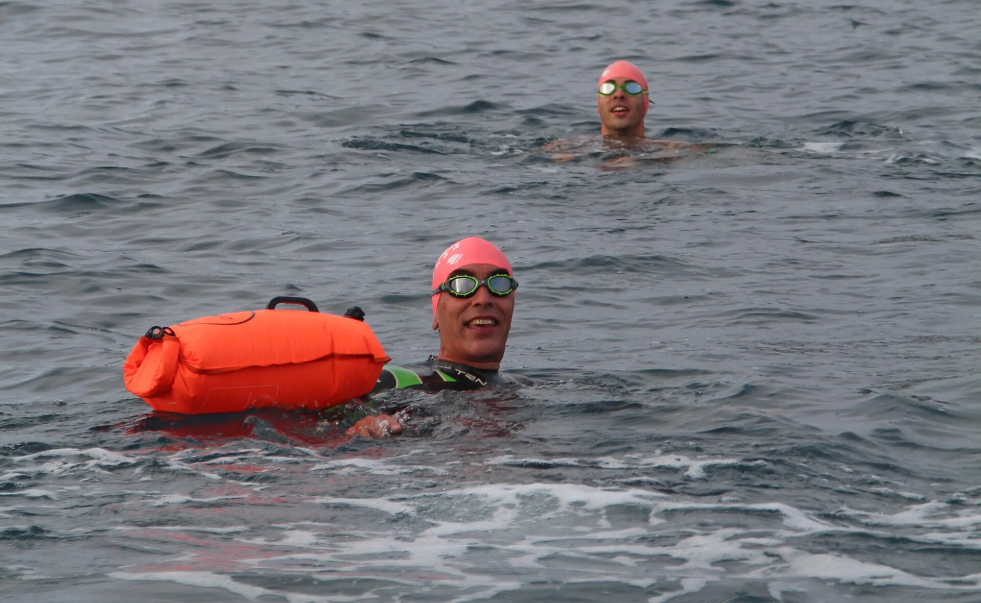 Mężczyźni pływający w jeziorze z bojką asekuracyjną 