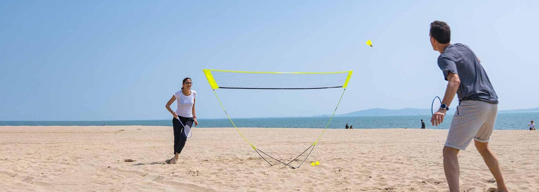 En man och en kvinna som spelar badminton på en strand