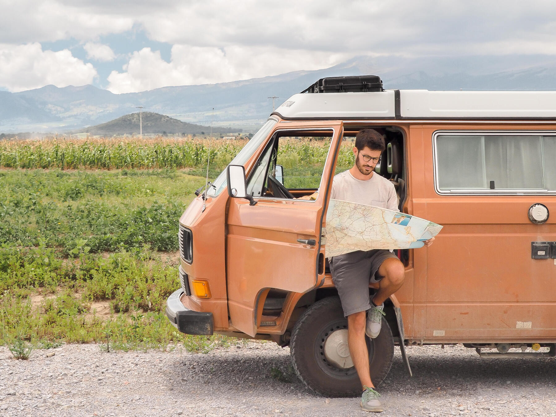 Eric en train de lire une carte, adossé à son van aménagé pendant un roadtrip