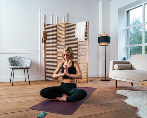 kobieta medytująca  na macie do jogi w domu