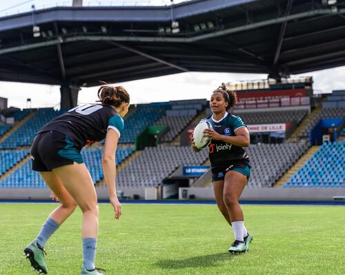 Two women playing rugby in stadium