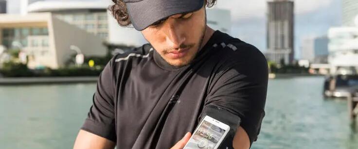 mężczyzna w odzieży do biegania trzymający telefon włożony do opaski biegowej na ramieniu