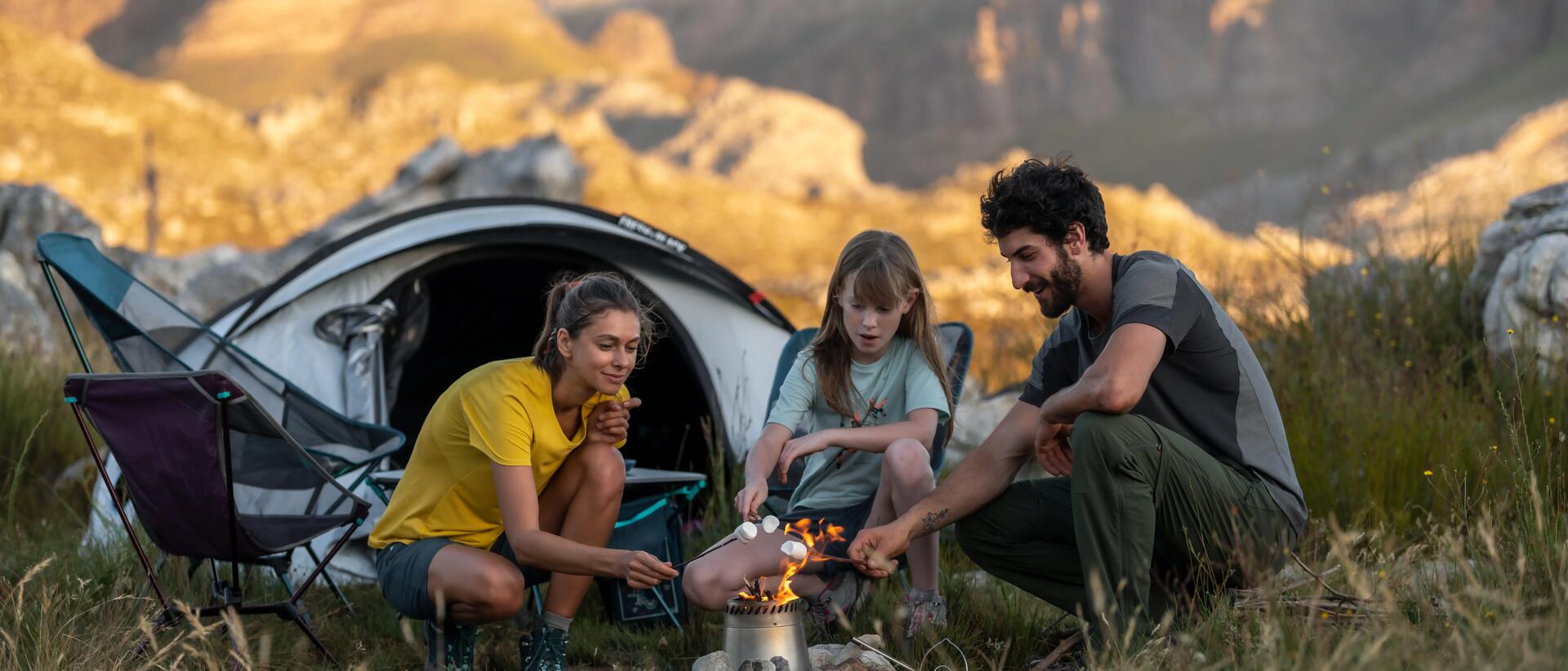 3 people camping outside and flaming marshmallows