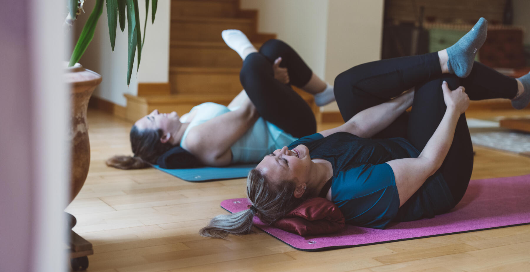 Två kvinnor som stretchar på en matta