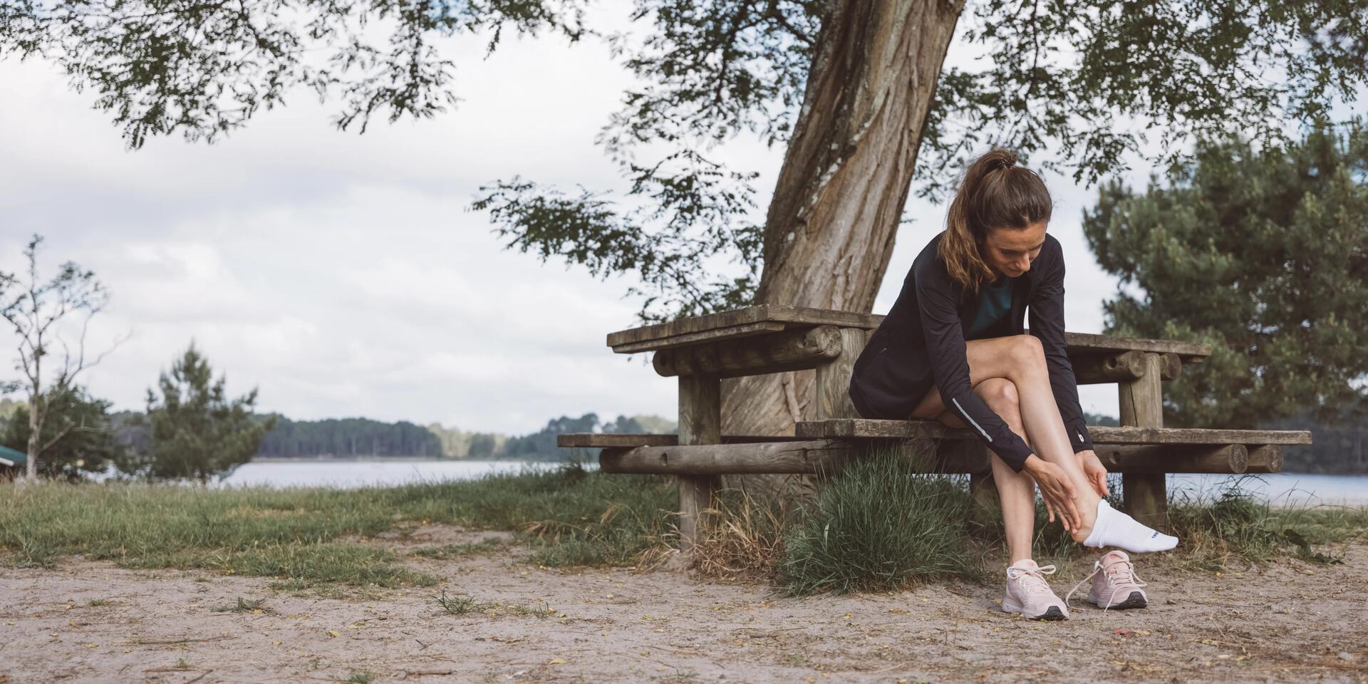 runner sitting on a bench taking off their sock