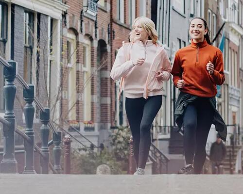 Two women running in city. 