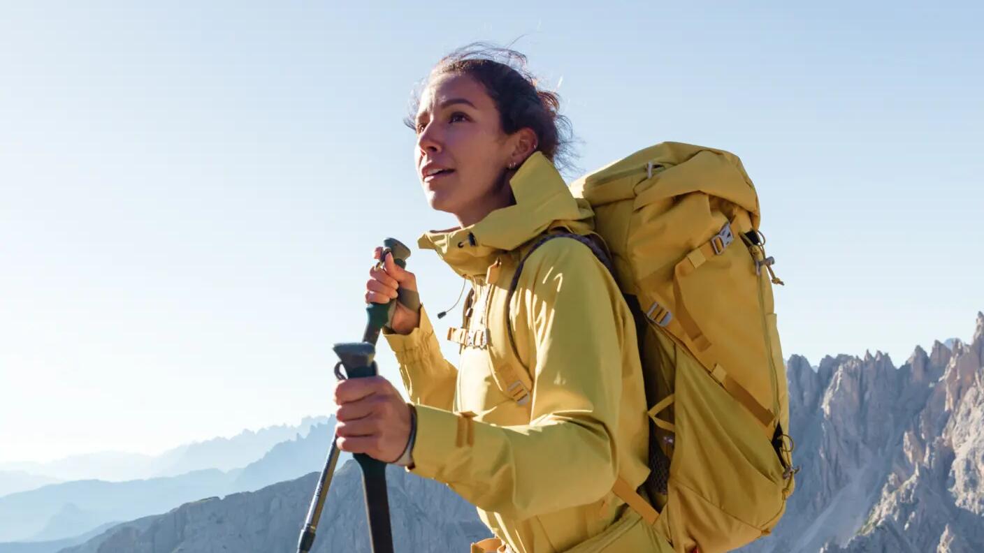 kobieta w kurtce trekkingowej z plecakiem na plecach wędrująca po górach