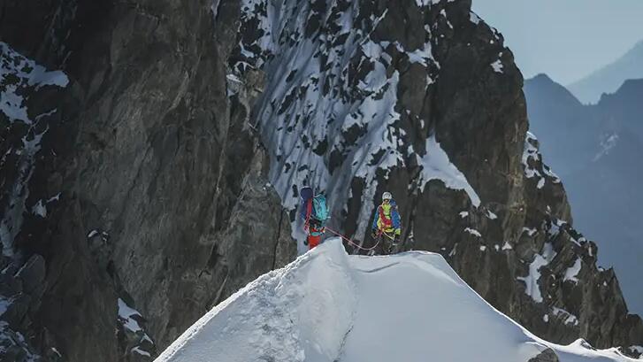 ludzie ubrani w stroje alpinistyczne z uprzężami w górach zimą