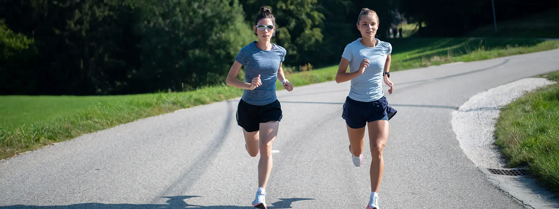 Two women running on road side by side