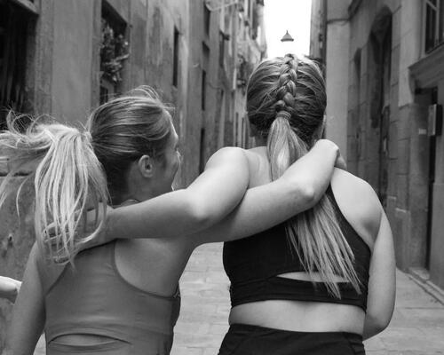 Four women walking together with arms around each other