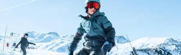 chłopiec w kasku i goglach snowboardowych zjeżdżający na desce snowboardowej ze stoku