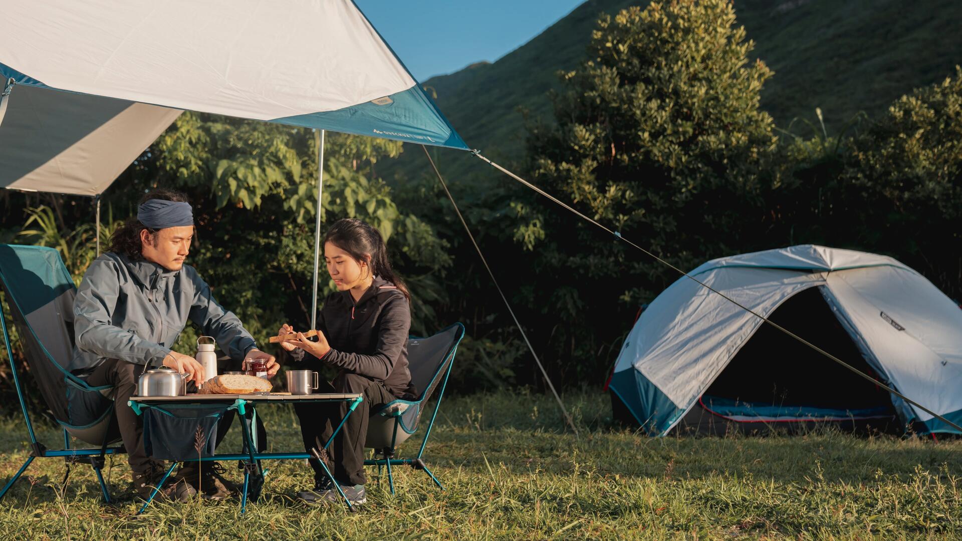 kobieta i mężczyzna siedzący przy stoliku turystycznym w plenerze przed namiotem