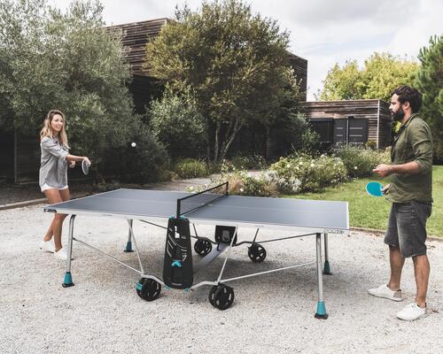 Man and woman playing table tennis outdoors