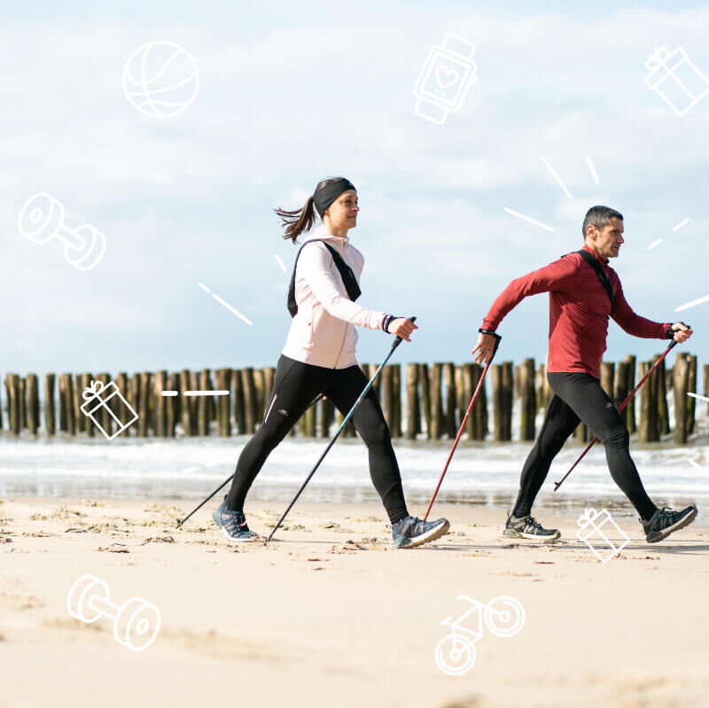 duas pessoas a caminhar na praia com bastoes