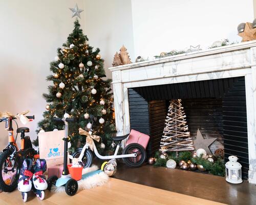 a room with bikes and scooters as gifts next to Christmas tree