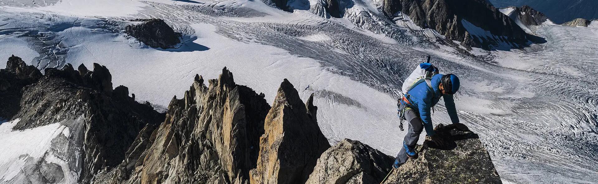 mężczyzna w stroju alpinistycznym wspinający się po górach zimą