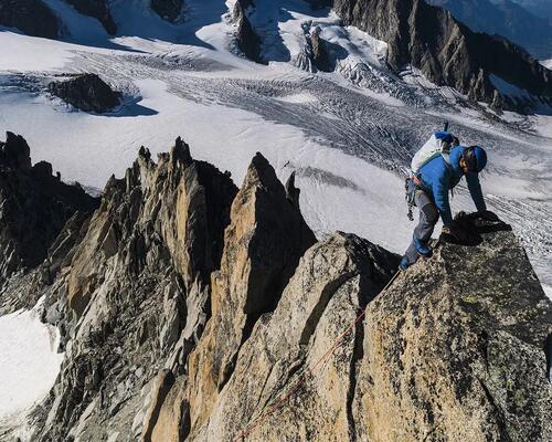 mężczyzna w stroju alpinistycznym wspinający się po górach zimą