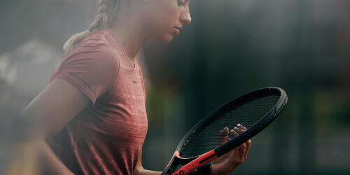 une femme ré-ajuste le cordage de sa raquette de tennis